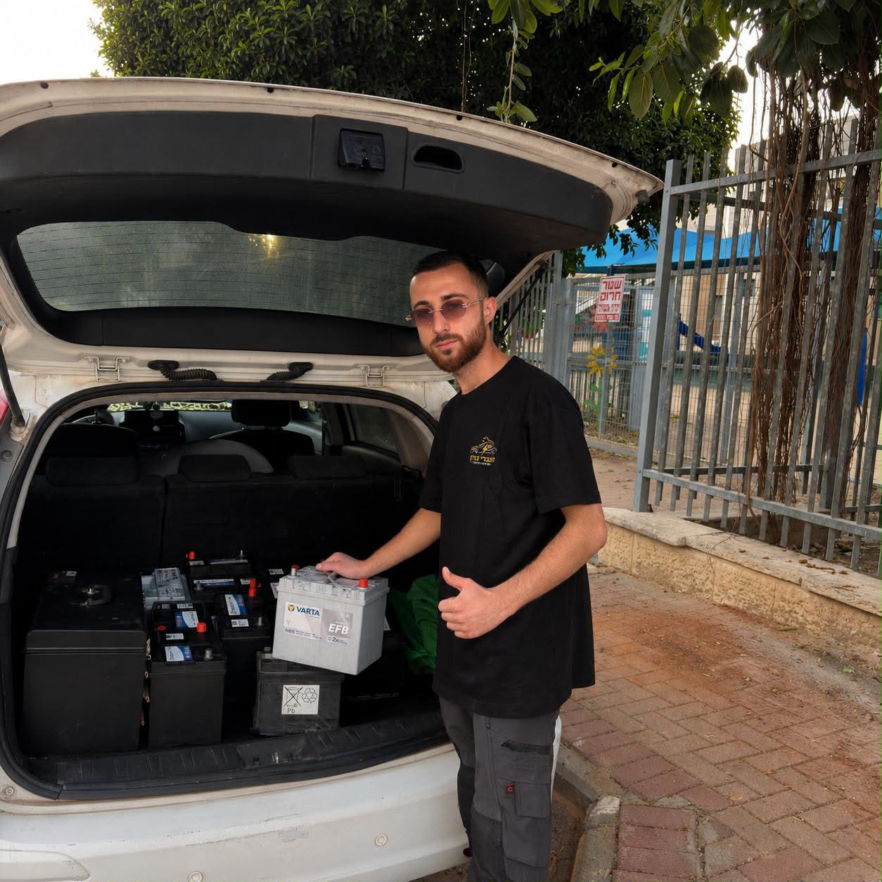 טכנאי עם מבחר מצברים חדשים ברכב השירות